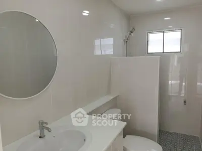 Modern bathroom with round mirror and sleek white fixtures