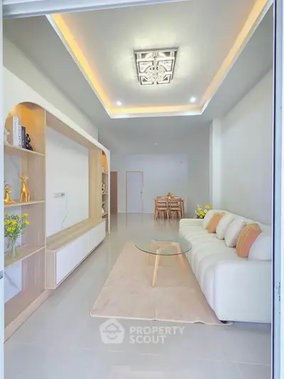 Modern living room with stylish decor and open layout, featuring a cozy sofa and elegant shelving.