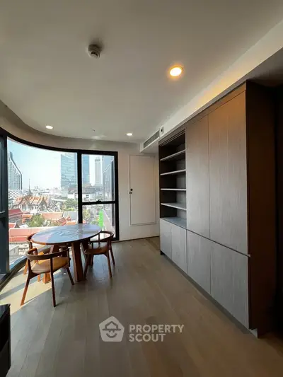Modern living room with city view, featuring sleek wooden flooring and built-in shelving.