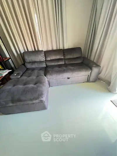 Spacious living room with plush gray sectional sofa and elegant curtains, perfect for relaxation.