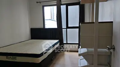 Cozy bedroom with large window and modern furnishings in urban apartment.