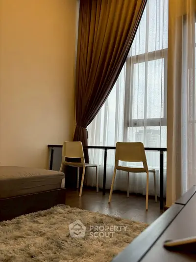 Cozy living room with tall windows, elegant curtains, and a plush rug for a warm ambiance.