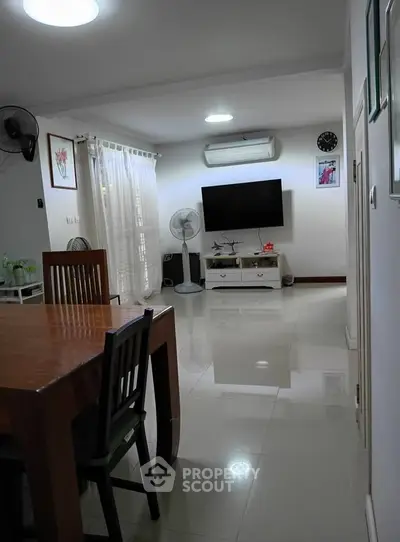 Spacious living room with modern decor and wall-mounted TV, perfect for family gatherings.