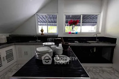 Modern kitchen with sleek black countertops and stacked white dishes, featuring a stylish open layout.