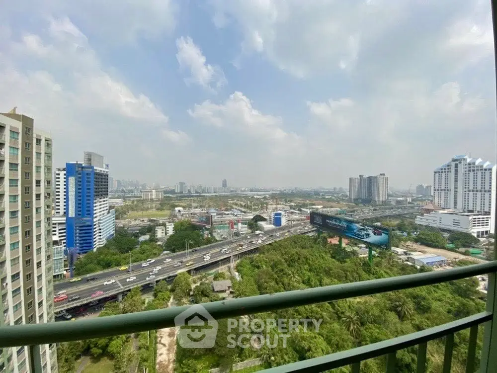 Stunning cityscape view from high-rise balcony overlooking lush greenery and urban skyline.