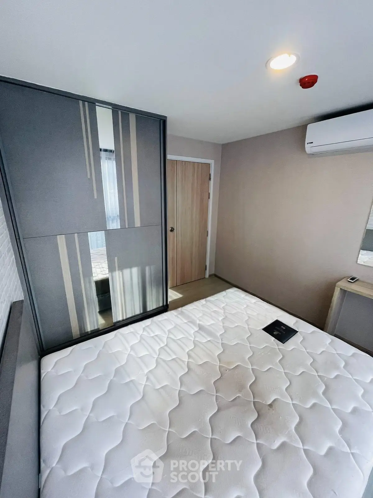 Modern bedroom with sleek wardrobe and air conditioning, featuring a comfortable mattress and stylish decor.