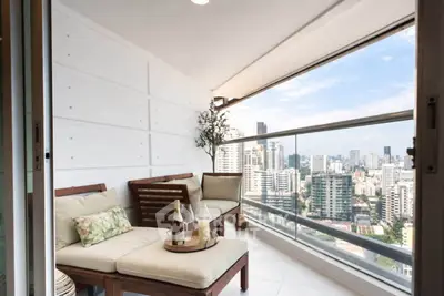 Luxurious balcony with stunning city view and cozy seating area in high-rise apartment.