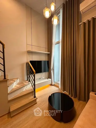 Modern living room with high ceilings, stylish lighting, and elegant staircase in a contemporary apartment.