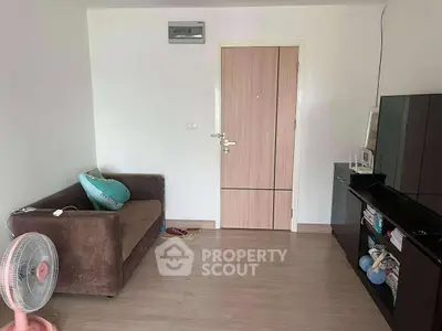 Cozy living room with modern decor and wooden flooring, featuring a comfortable sofa and entertainment unit.