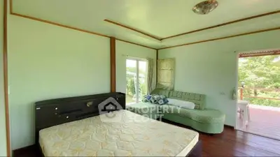 Spacious bedroom with large windows and balcony access, featuring a cozy seating area and serene views.