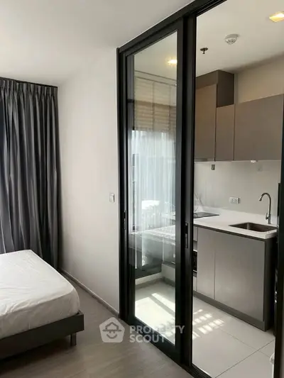 Modern studio apartment with sleek kitchen and cozy bedroom, featuring floor-to-ceiling windows and elegant curtains.