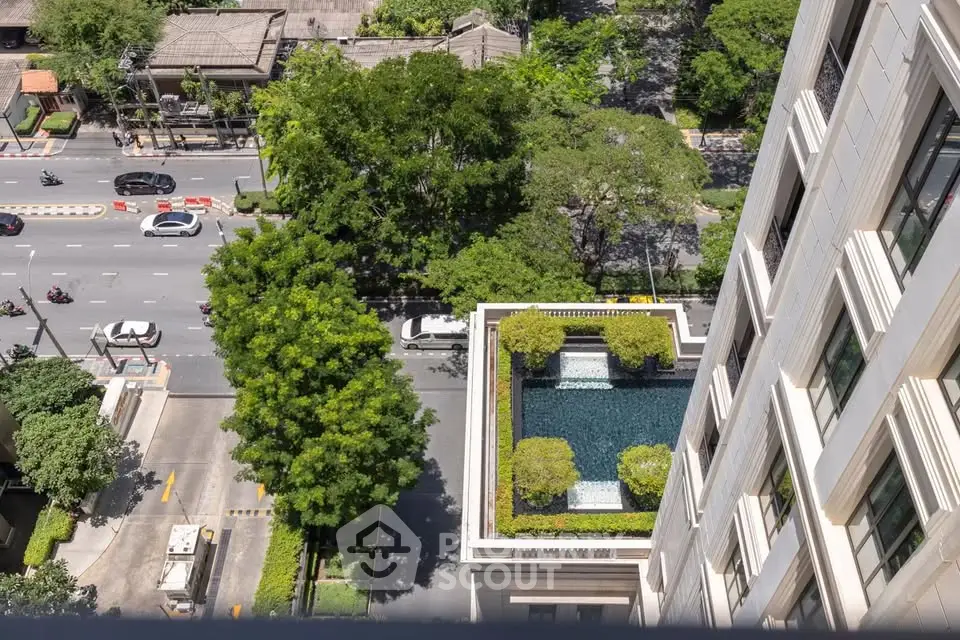 Stunning aerial view of luxury building with rooftop pool and lush greenery in urban setting.