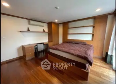 Spacious bedroom with wooden flooring and modern furnishings