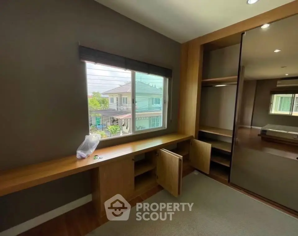 Spacious bedroom with built-in wooden storage and large window view.