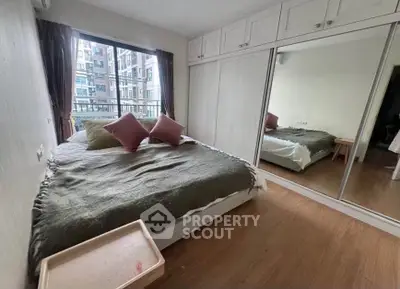 Cozy bedroom with large window and mirrored closet in modern apartment.