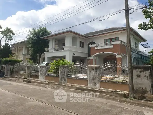 Spacious two-story house with gated entrance and lush greenery