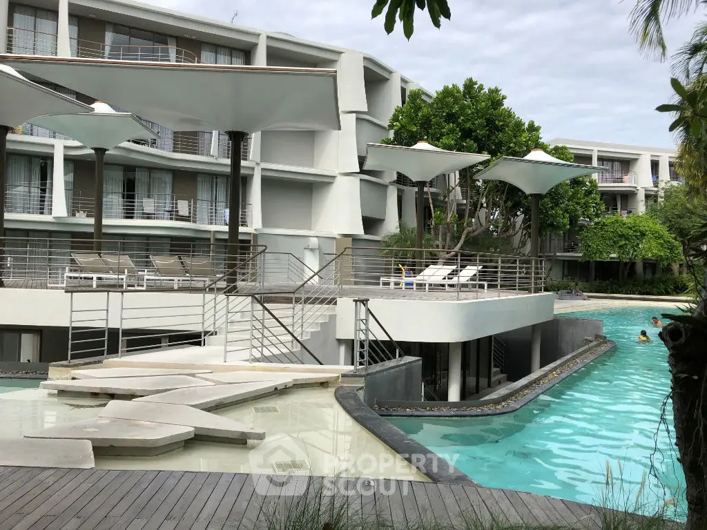 Luxurious modern apartment complex with stunning pool and lush greenery, perfect for resort-style living.