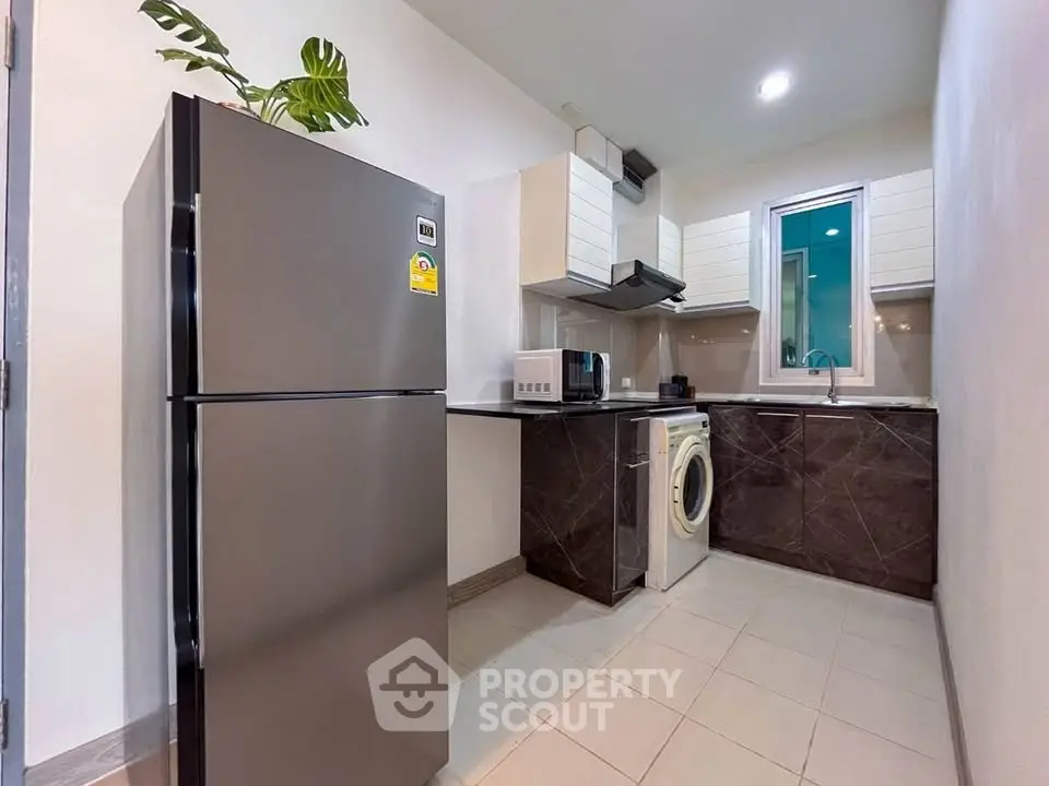Modern kitchen with sleek appliances and washing machine in compact layout
