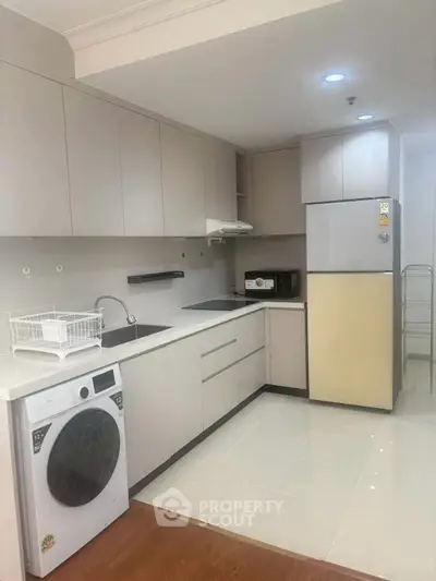 Modern kitchen with sleek cabinetry and built-in appliances, featuring a washing machine and microwave.