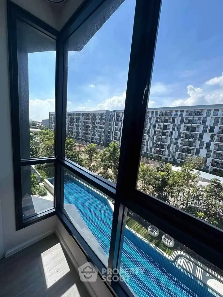 Stunning high-rise view from a modern apartment balcony overlooking a pool and urban landscape.