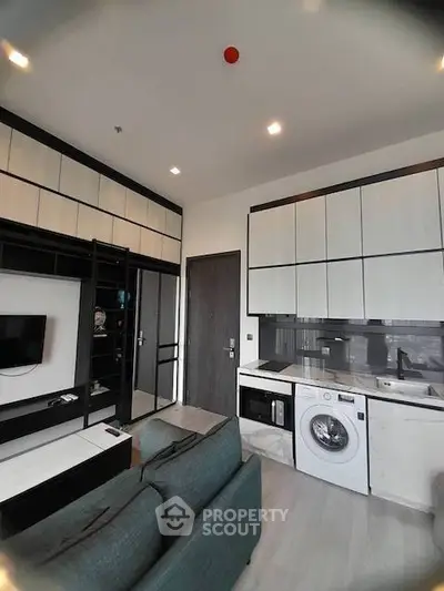 Modern living room with integrated kitchen and washing machine in stylish apartment.