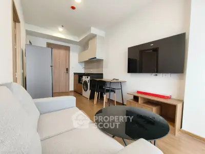 Modern living room with open kitchen, featuring sleek appliances and cozy seating area.