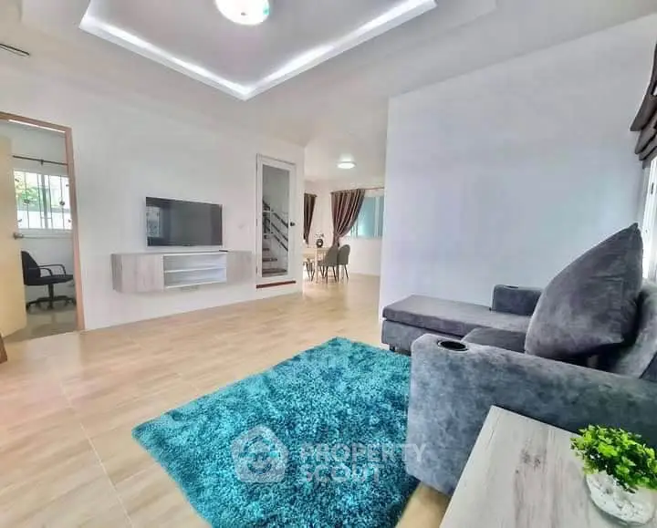 Spacious modern living room with plush gray sofa and vibrant blue rug