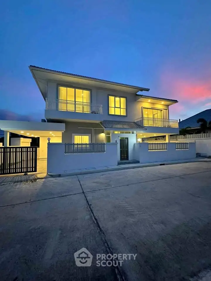 Stunning two-story modern home with illuminated windows and spacious driveway at dusk.