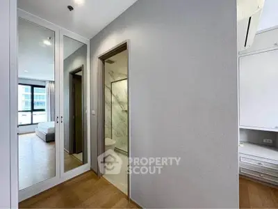 Modern bedroom with ensuite bathroom and mirrored closet doors in a stylish apartment.