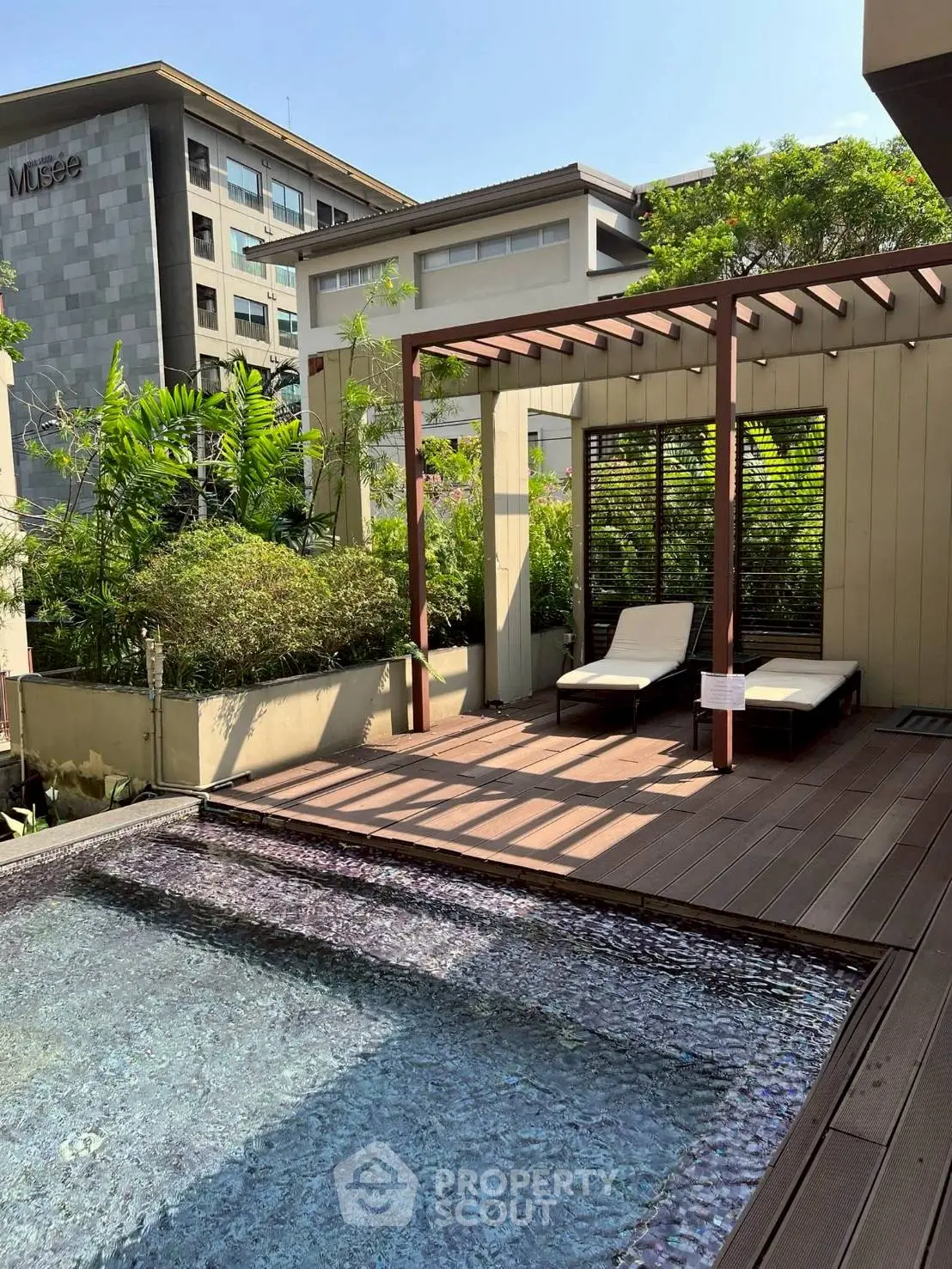 Luxurious rooftop pool with sun loungers and pergola, perfect for relaxation and leisure.