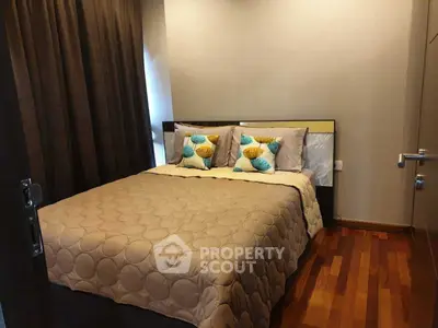 Cozy bedroom with wooden flooring and stylish bedding in modern apartment.