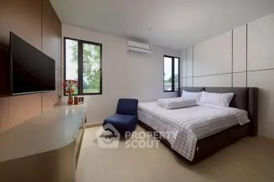 Modern bedroom with stylish decor, featuring a comfortable bed, sleek furniture, and natural light from large windows.