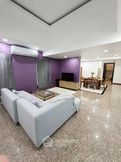 Spacious modern living room with elegant decor and open dining area, featuring plush seating and sleek flooring.