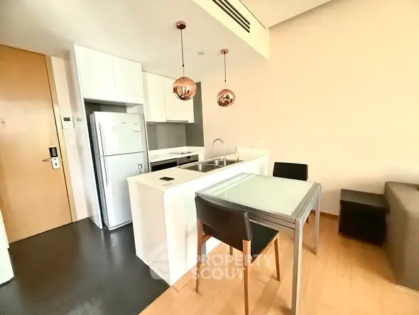 Modern kitchen with sleek design, featuring a compact dining area and stylish lighting.
