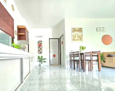 Bright and spacious living area with dining set and cozy seating, perfect for family gatherings.
