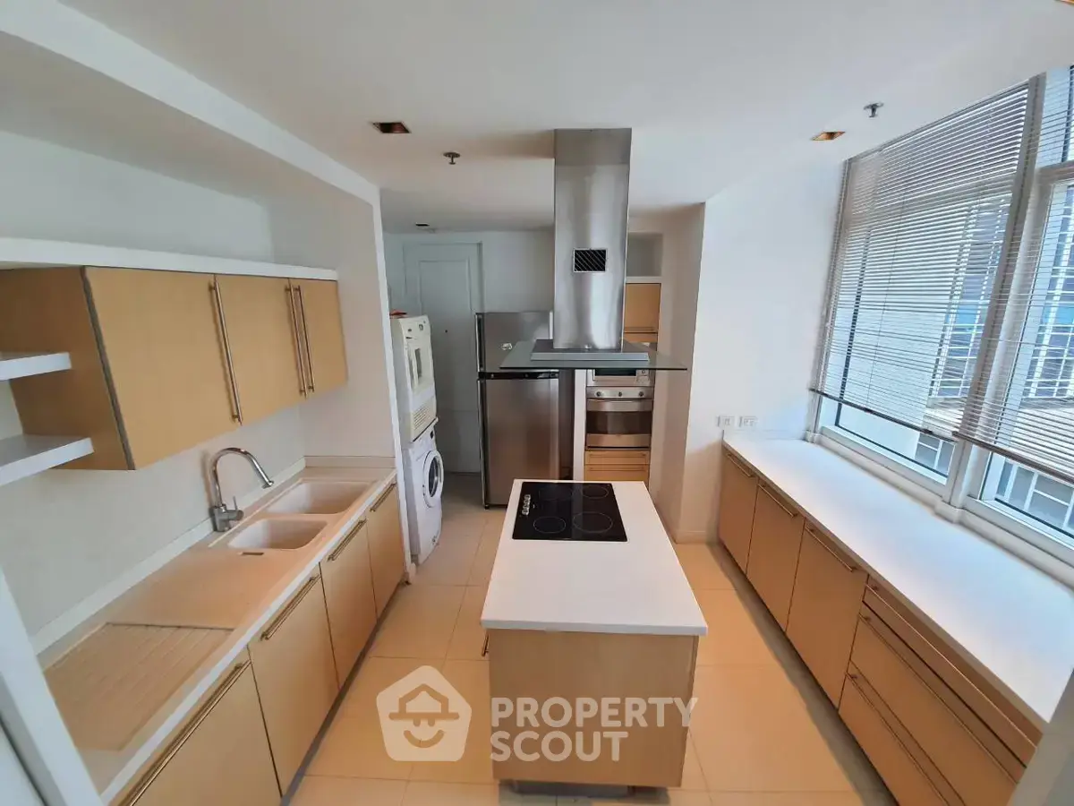 Spacious modern kitchen with island and ample natural light, featuring sleek cabinetry and built-in appliances.