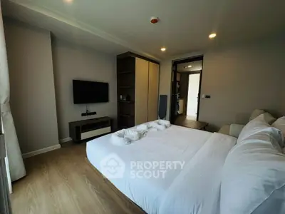 Modern bedroom with cozy decor and flat-screen TV, perfect for relaxation.