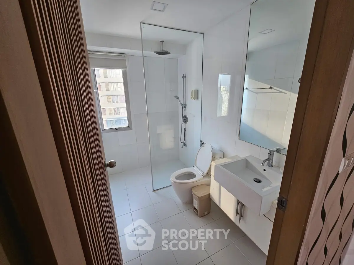 Modern bathroom with glass shower and sleek fixtures in bright apartment.