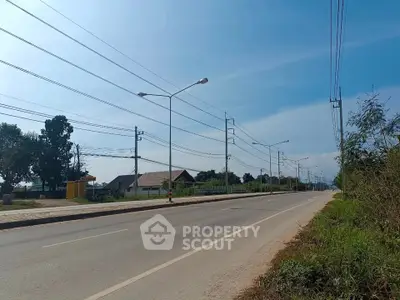 Scenic road view with clear skies and residential area, ideal for real estate development.
