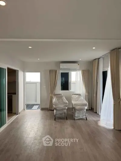 Spacious living room with large windows and modern flooring in a bright apartment.