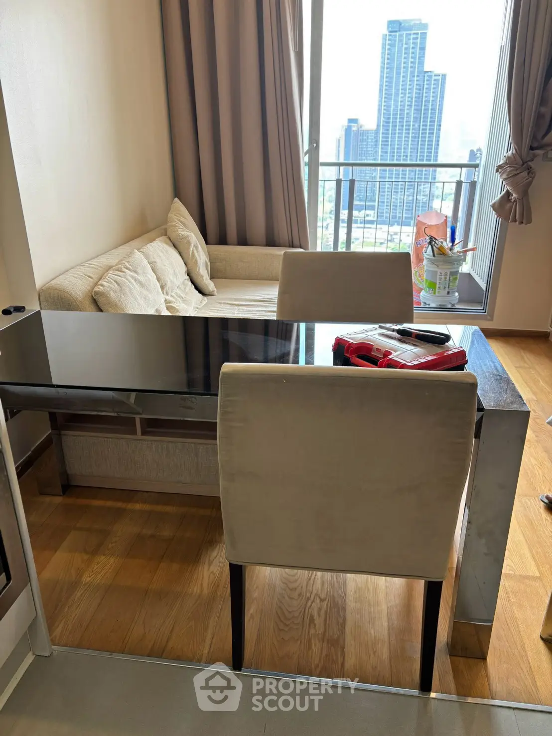 Modern living room with city view, featuring sleek furniture and floor-to-ceiling windows.