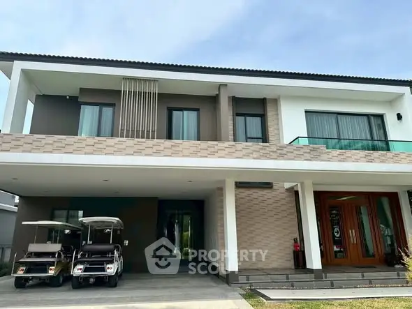 Modern two-story house with spacious balcony and golf carts in driveway.