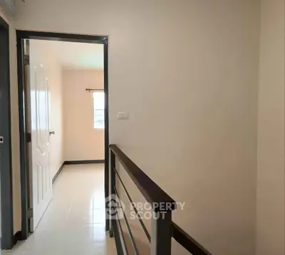 Bright hallway leading to a sunlit room with modern railing and neutral tones.