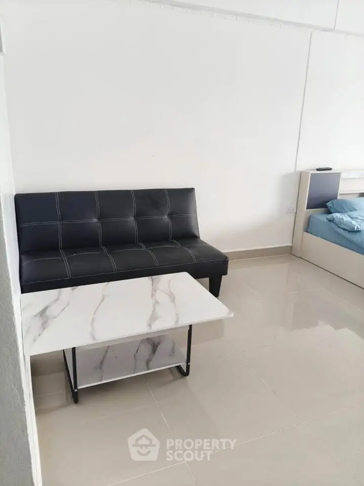 Modern minimalist living room with sleek black sofa and marble coffee table.