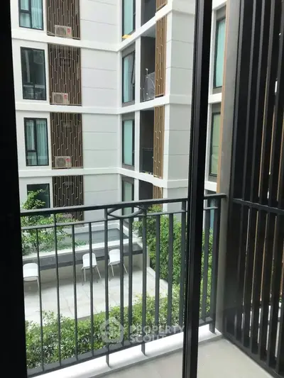 Modern apartment balcony with view of stylish building courtyard and greenery.
