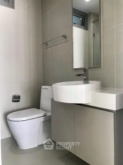 Modern bathroom with sleek fixtures and neutral tones, featuring a stylish sink and toilet.