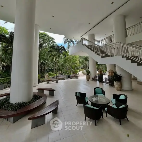 Luxurious open-air lobby with modern seating and lush garden views, perfect for relaxation and social gatherings.
