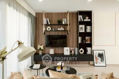 Modern living room with stylish decor and wall-mounted TV, featuring elegant shelving and cozy seating.