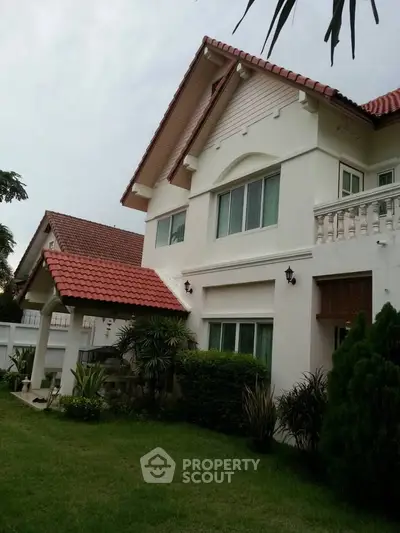 Charming two-story house with red-tiled roof and lush garden