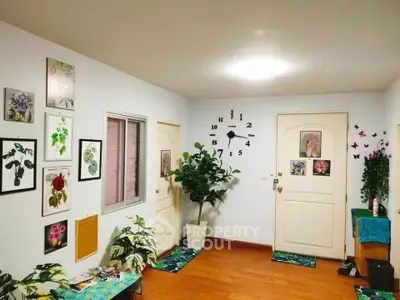 Charming interior hallway with vibrant decor and wooden flooring, featuring wall art and lush plants.